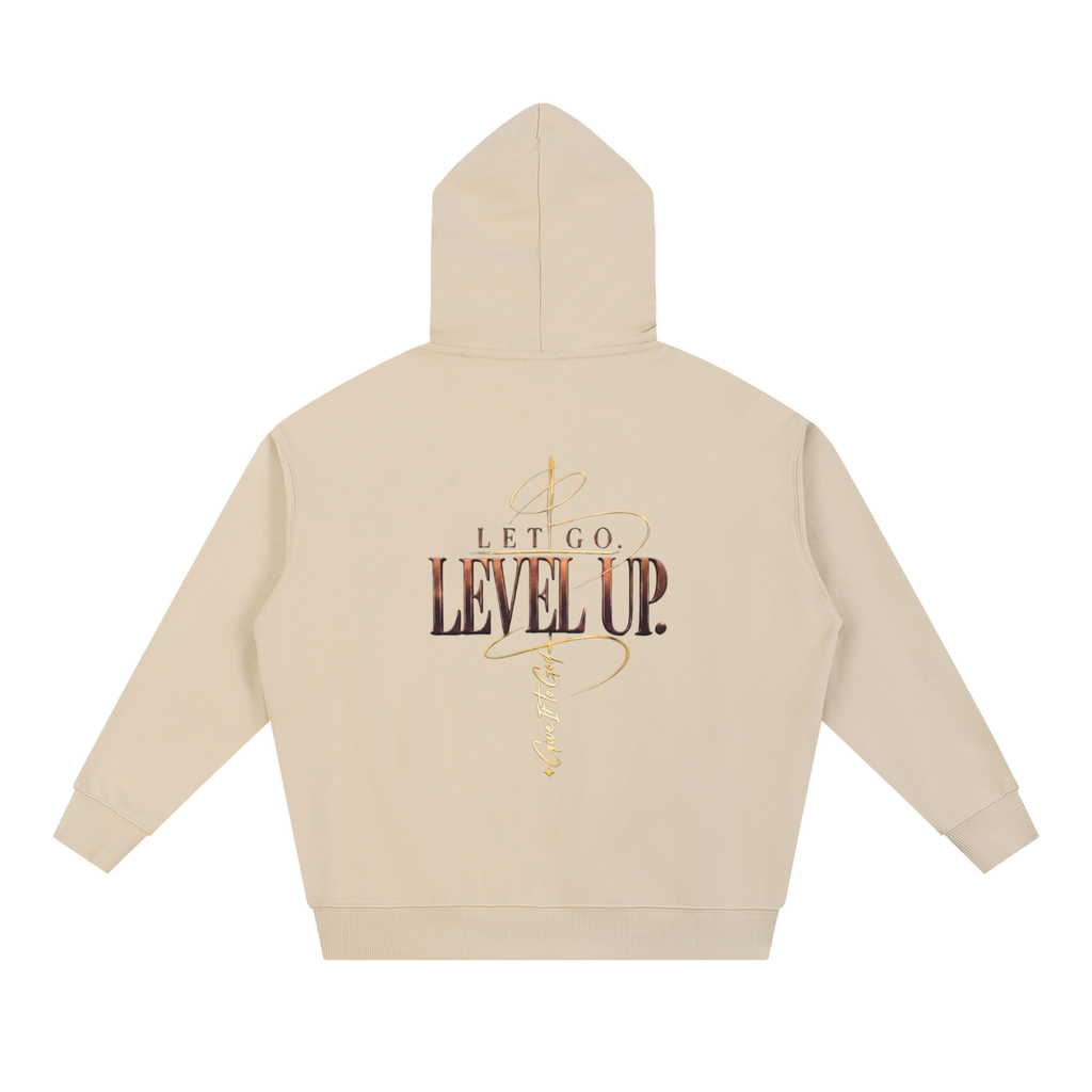 Give It To God oversized beige hoodie featuring a metallic gold Let Go. Level Up. graphic on the back.
